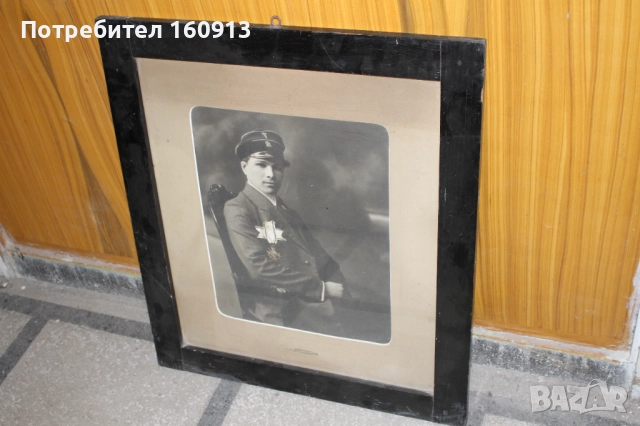 Войнишки кръст за храброст в старинна дървена рамка със снимка.