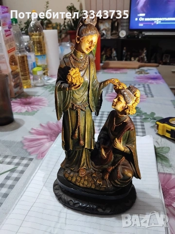 Статуетката изобразява две китайски жени в традиционно облекло.