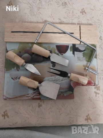 Стъклен поднос за сирене с дървена основа и принадлежности за рязане.